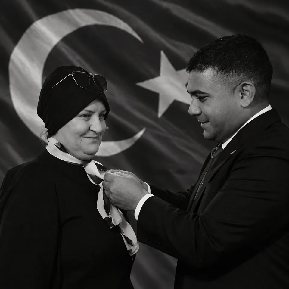 Genel Başkan Teoman Mutlu, Türk bayrağı önünde Kadın Komisyonu Başkanı Ayşe Gürkan’a rozetini takıyor