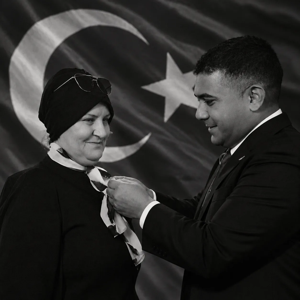 Genel Başkan Teoman Mutlu, Türk bayrağı önünde Kadın Komisyonu Başkanı Ayşe Gürkan’a rozetini takıyor